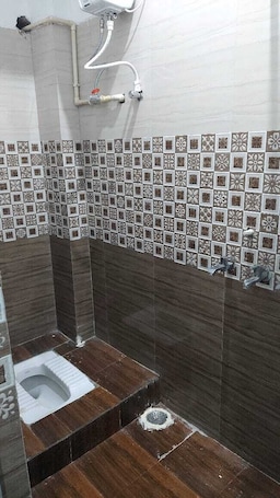 A bathroom with a shower, a toilet, and a sink.. Bhagalpur Rest House Palace Ashish