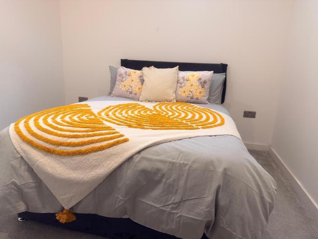 Ein Bett mit einer gemusterten Decke, Kissen und einem Kopfteil.