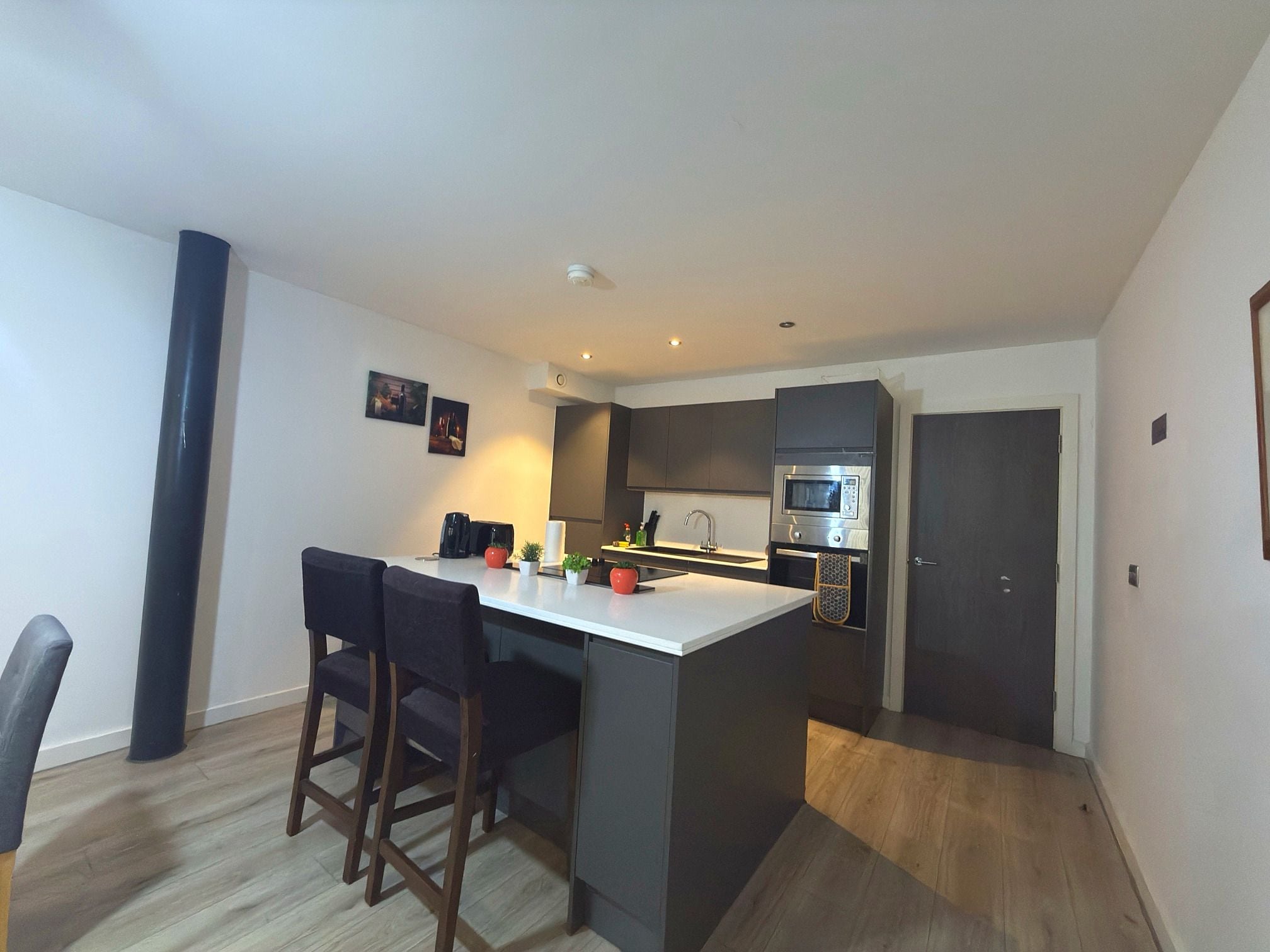 A compact kitchen with a central island, dark cabinetry, and a microwave.