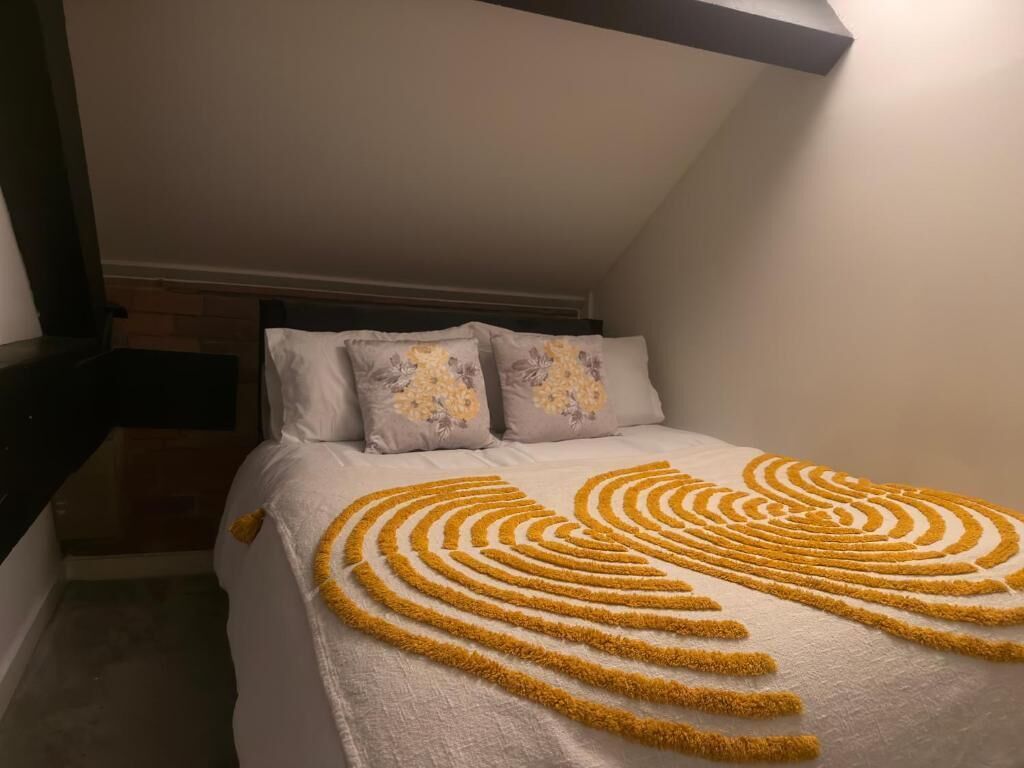 Une chambre à coucher avec un lit, des oreillers et un motif décoratif en forme de cœur sur la couvre-lit.