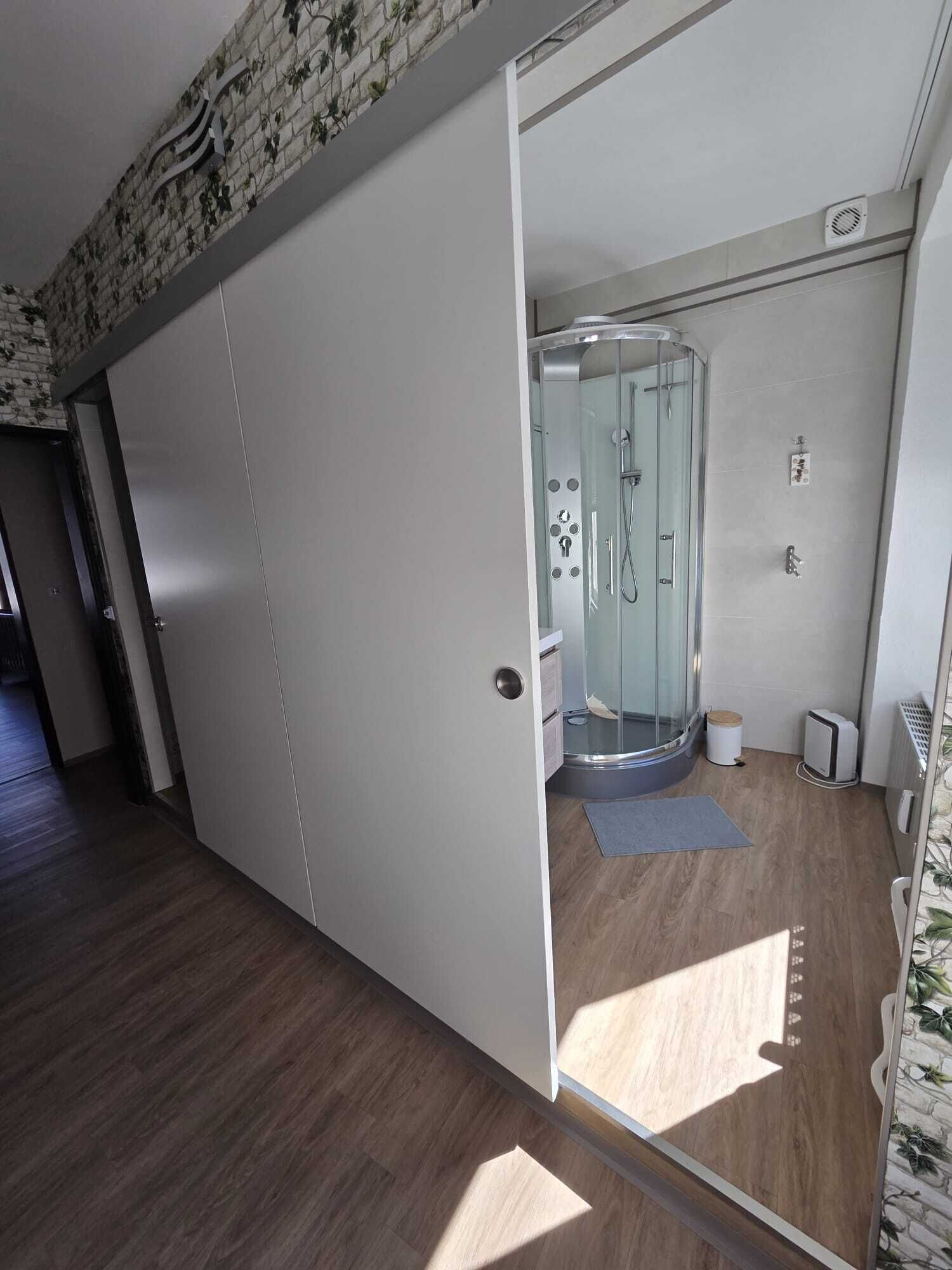 Een moderne badkamer met een douchecabine van glas, een toilet en een kleine prullenbak.