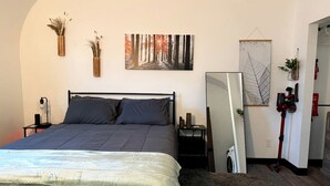 Ein Schlafzimmer mit Bett, Nachttisch, Spiegel und einem Wandbild.