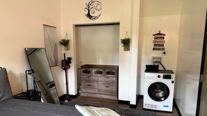 Een slaapkamer met een bed, een dressoir, een wasmachine en een spiegel.