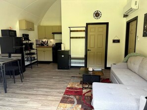 A compact living space with a kitchenette, a dining area, and a sofa.