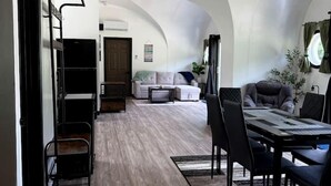 Een ruime woonkamer met een hoge plafond, een eettafel met stoelen, een bank en een salontafel.