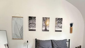 Ein Schlafzimmer mit einem Bett, einem Nachttisch, einer Lampe und Wandbildern.