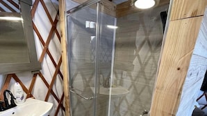 A bathroom with a glass shower enclosure, a white sink, and wooden beams. - Luxury Yurt makes for a Brilliant Texan Retreat (Mineral Wells)