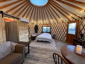 Interieur van een joert met een bed, zithoek en een eettafel.