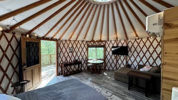 A yurt interior with a bed, seating area, and a table.