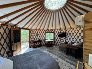 A yurt interior with a bed, seating area, and a table.