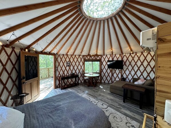 A yurt interior with a bed, seating area, and a table.