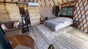 Ein gemütliches Jurte mit einem Bett, einem kleinen Tisch und einer Couch.