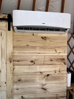 A white air conditioning unit mounted on a wooden wall with visible grain patterns.