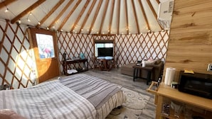 A yurt with a bed, a TV, a desk, and a small table. - Luxury Yurt makes for a Brilliant Texan Retreat (Mineral Wells)