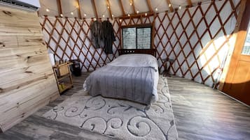 Ein gemütliches Zimmer mit einem Bett, Holzwänden, einem Fenster und einer Kleiderstange.
