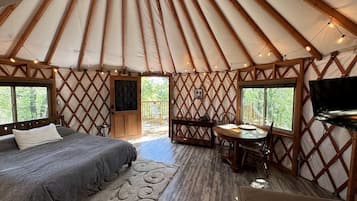 Indretning i en yurt med seng, spiseplads og fjernsyn.