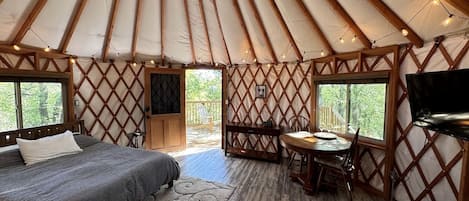 Interieur van een joert met een bed, een eethoek en een televisie.