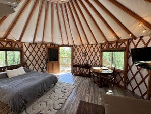 Interno di una yurta con un letto, un'area pranzo e una TV.
