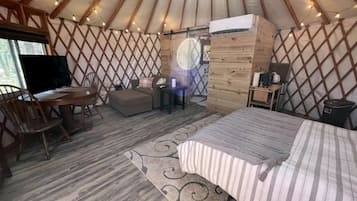 A yurt with a bed, a desk, and a chair.
