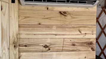 Un appareil de climatisation blanc, fixé à un mur en bois dont on peut voir les motifs du grain du bois.