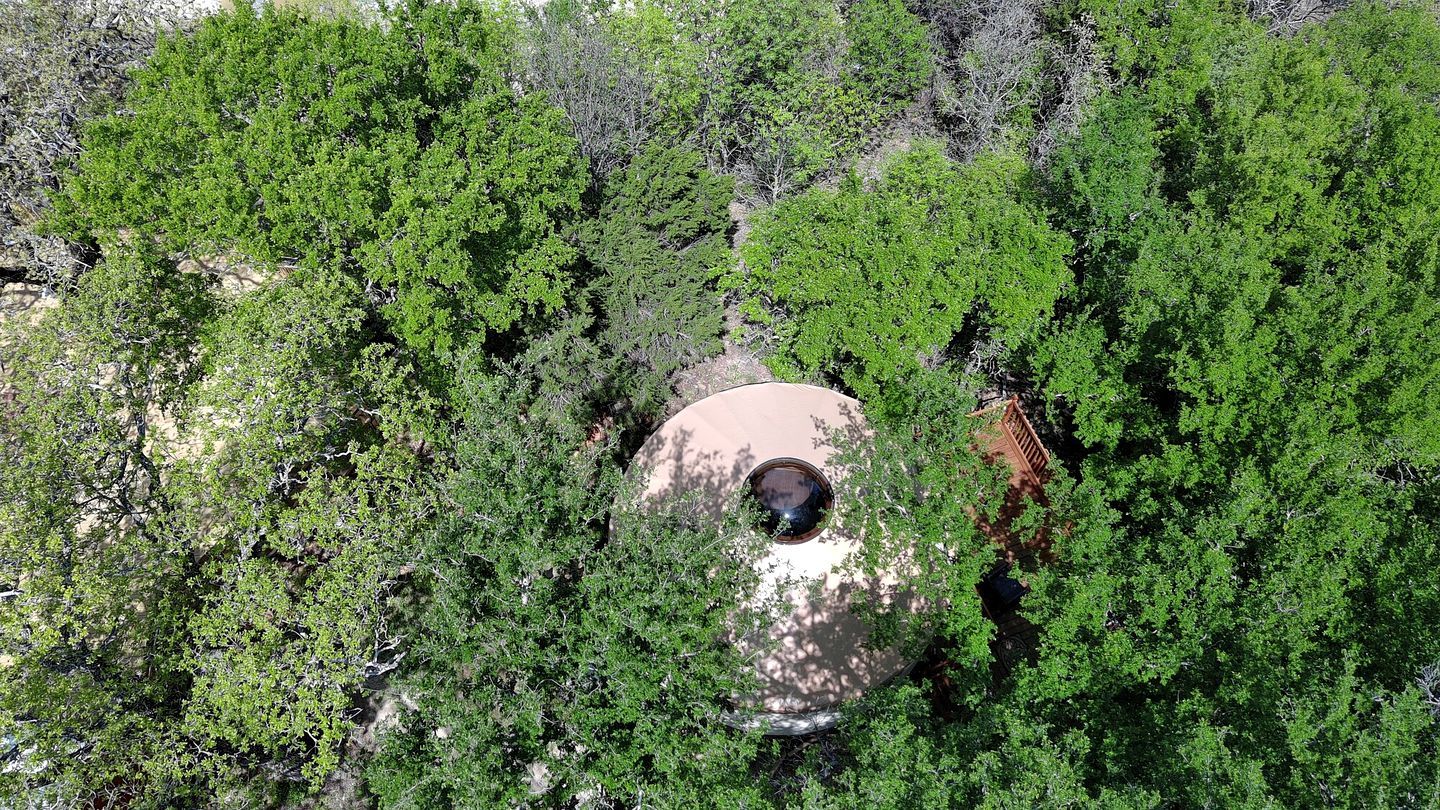 An aerial view of a building surrounded by dense green foliage.