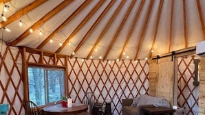 A yurt interior with a round dining table, wooden chairs, a sofa, and a bed. - Luxury Yurt makes for a Brilliant Texan Retreat (Mineral Wells)