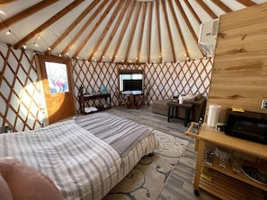 Een joert met een bed, een televisie, een bureau en een kleine tafel.