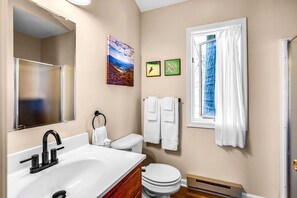 Une salle de bain avec un lavabo, des toilettes et une fenêtre avec des rideaux.