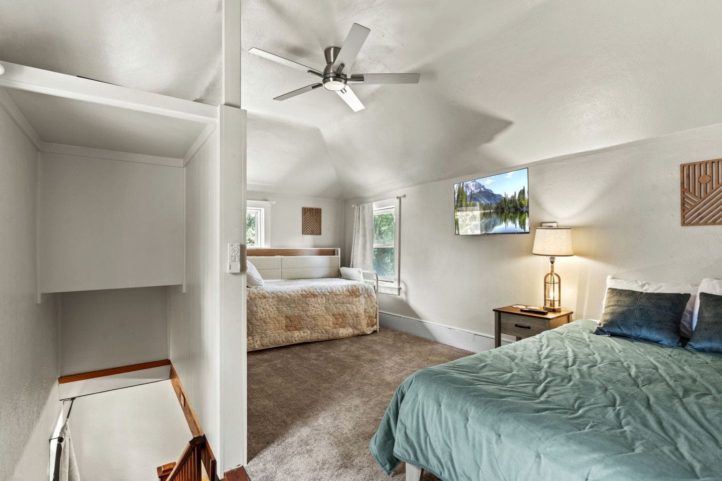 A bedroom with a bed, a nightstand, a lamp, a ceiling fan, and a window.