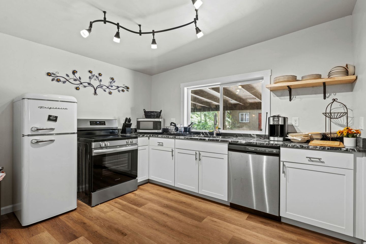 Una cocina moderna con electrodomésticos de acero inoxidable, armarios blancos y suelo de madera.