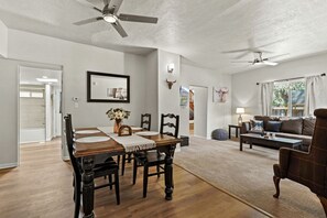 Ein geräumiges Wohnzimmer mit Essbereich, Deckenventilatoren und einem großen Fenster.
