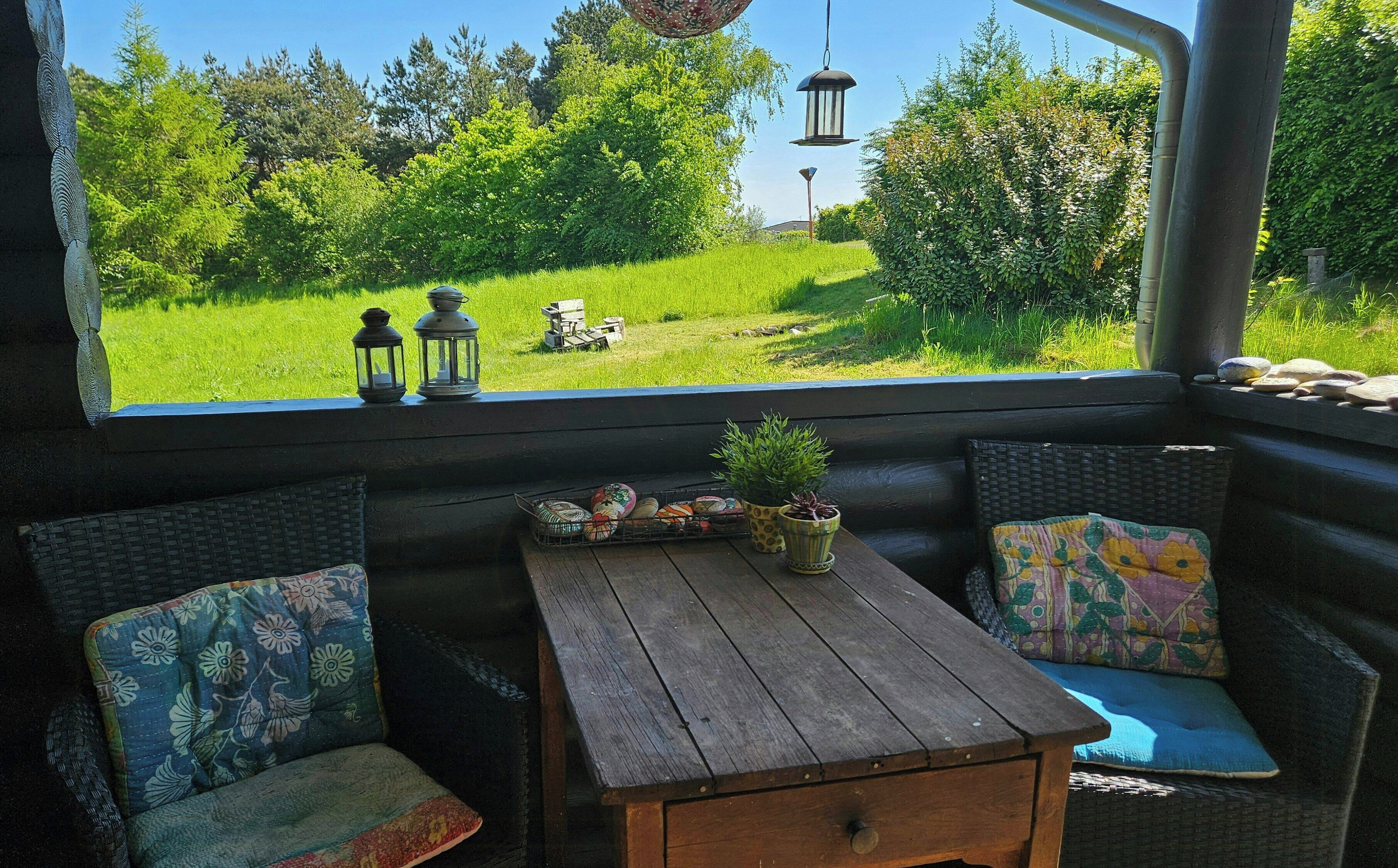 A cozy seating area with a view of a lush garden, a small table with decorative items, and two lanterns.