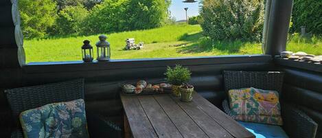 A cozy seating area with a view of a lush garden, a small table with decorative items, and two lanterns.