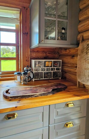 Eine Küche mit einer Holzarbeitsplatte, einer Kaffeemaschine und einem Schrank mit Glastüren.