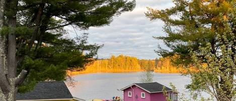 A lakeside cabin with a dock, a small shed, and a yellow building.