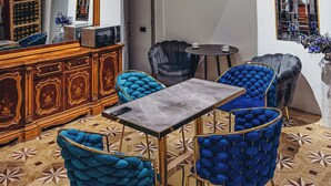 A multi-level interior with a chandelier, a dining area with blue upholstered chairs, a wooden cabinet, and a balcony with a wrought iron railing. - Pushkin Hotel Yerevan (Yerevan)