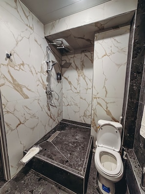 Un baño con ducha, inodoro y paredes de mármol.
