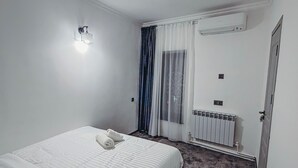 A hotel room with a bed, a wall-mounted air conditioner, a radiator, and a door. - Pushkin Hotel Yerevan (Yerevan)