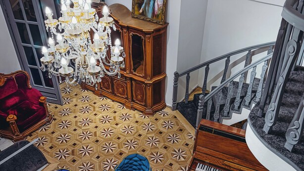 A grand room with a chandelier, a piano, a blue sofa, a red chair, and a patterned floor. - Pushkin Hotel Yerevan (Yerevan)