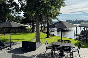 Eine Terrasse mit Gartenmöbeln, Blick auf einen See und ein Pavillon.