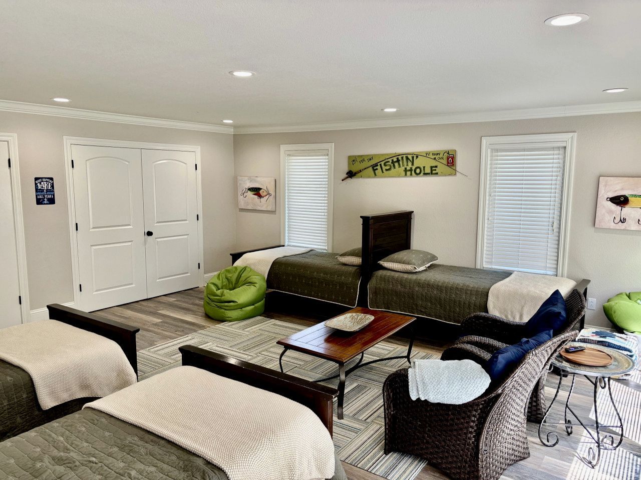 A bedroom with two beds, a sofa, a coffee table, and a green bean bag.