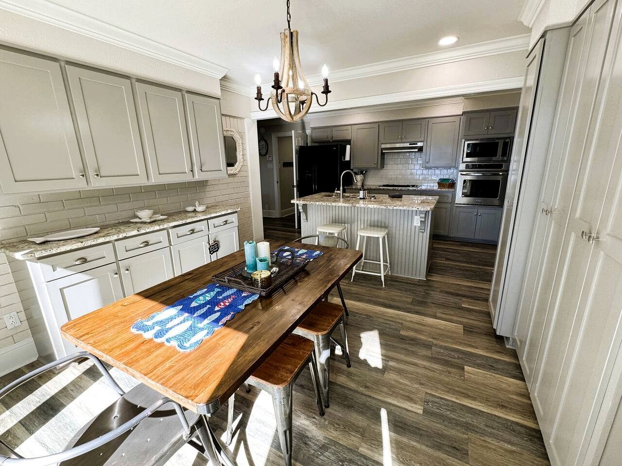 A kitchen with a central island, white cabinetry, stainless steel appliances, and a chandelier.