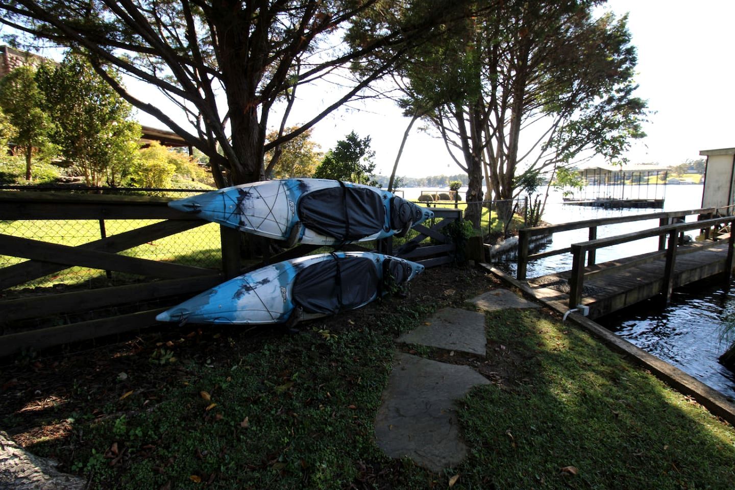 Kayaks tied to a fence near a body of water.