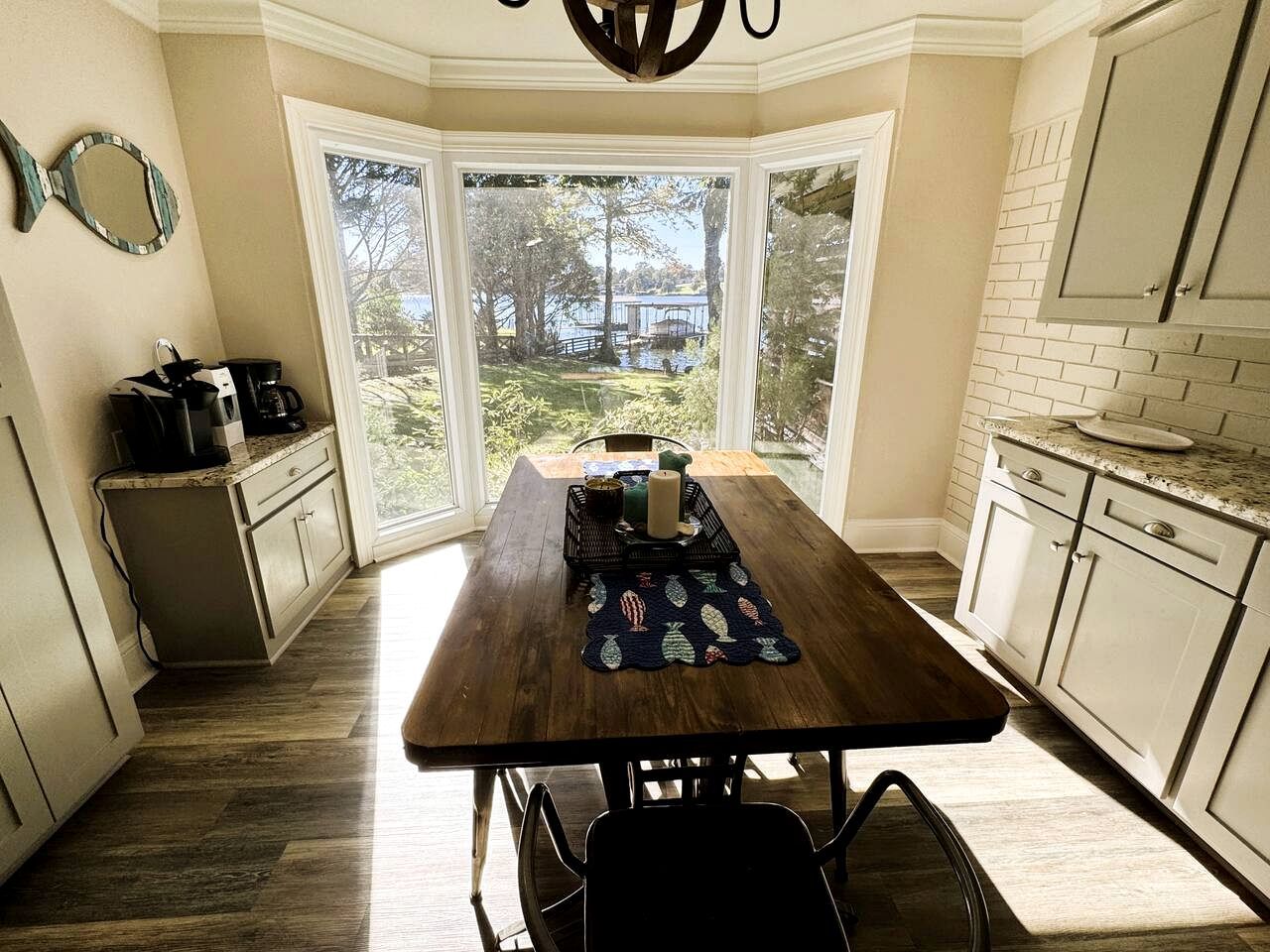 A kitchen with a wooden table, a view of the outdoors, and a brick wall.