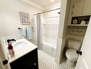 Ein Badezimmer mit einem weißen Waschbecken, einer Duschvorhang, einer Toilette und einem Regal mit Dekoration.