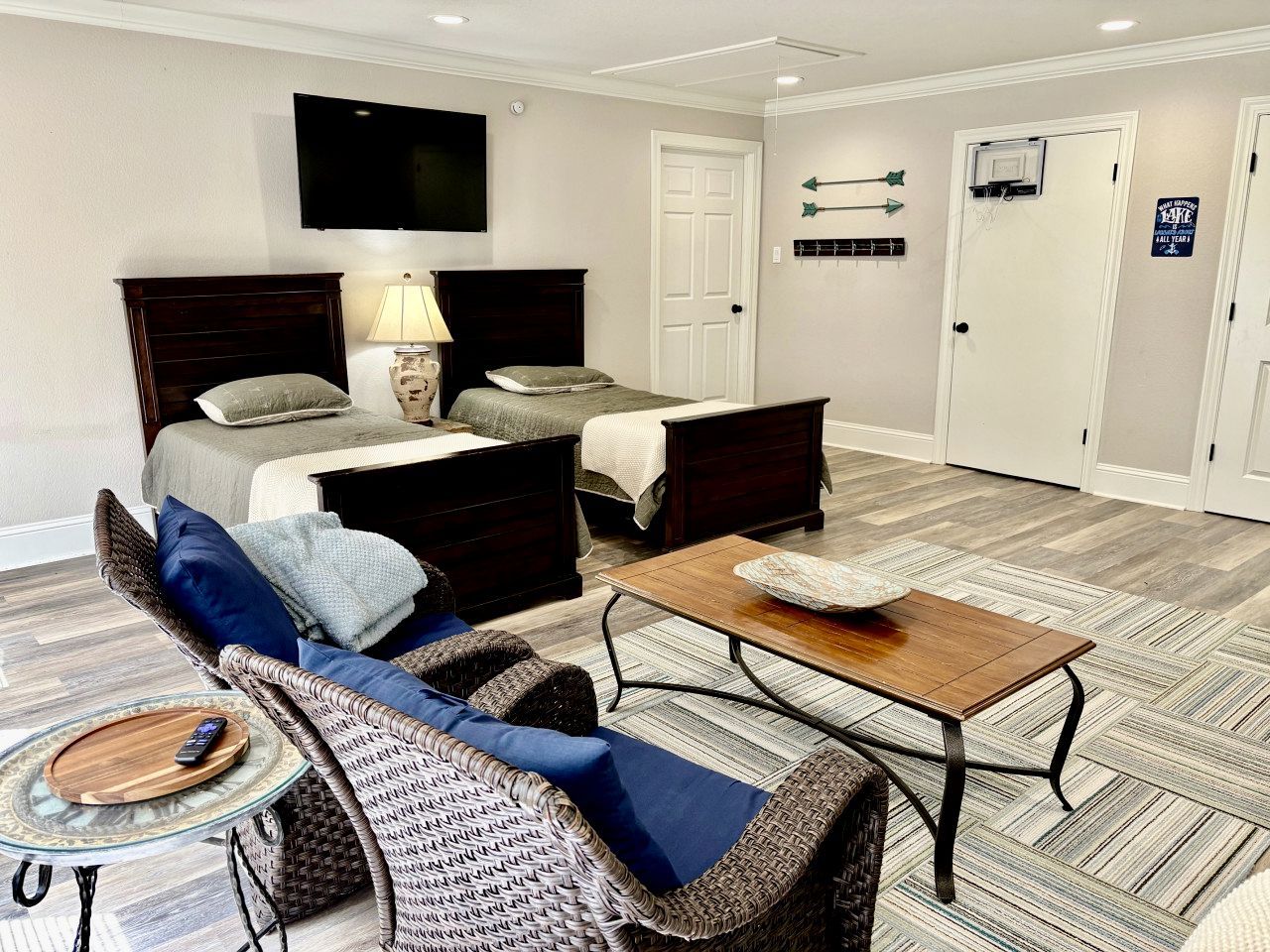A bedroom with a bed, bedside tables, a TV, and a door with a sign.