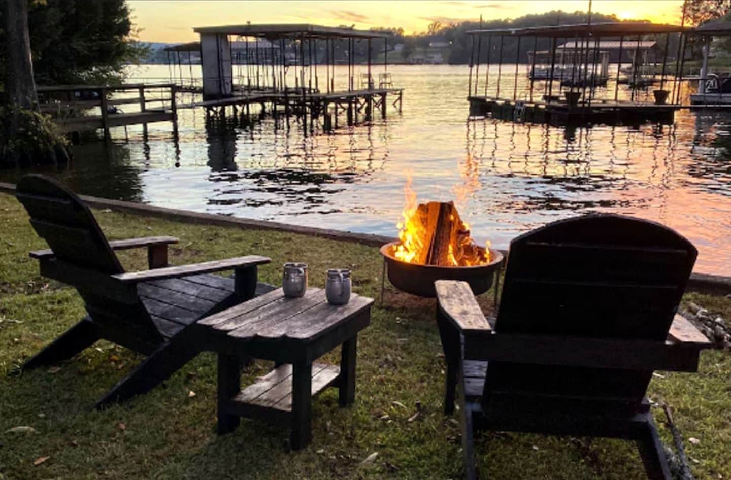 A lakeside setting with wooden chairs and a fire pit.