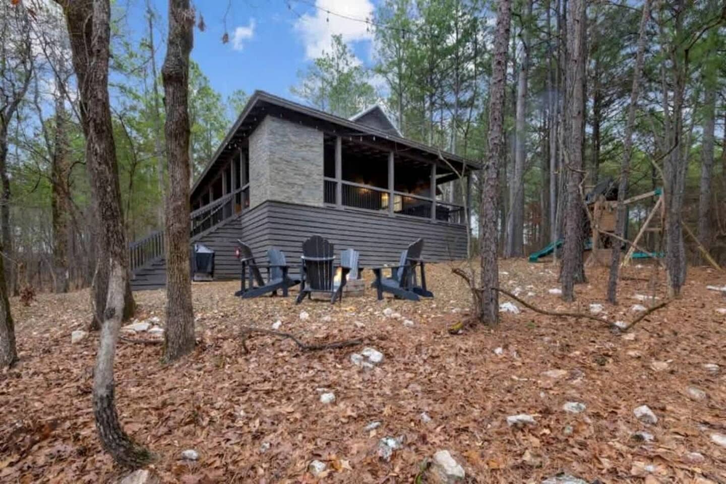 Eine Holzhütte mit Steinfassade, einer Terrasse und Sitzgelegenheiten im Freien.