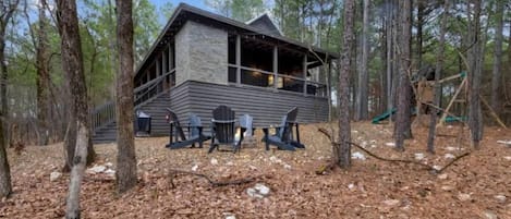 Eine Holzhütte mit Steinfassade, einer Terrasse und Sitzgelegenheiten im Freien.