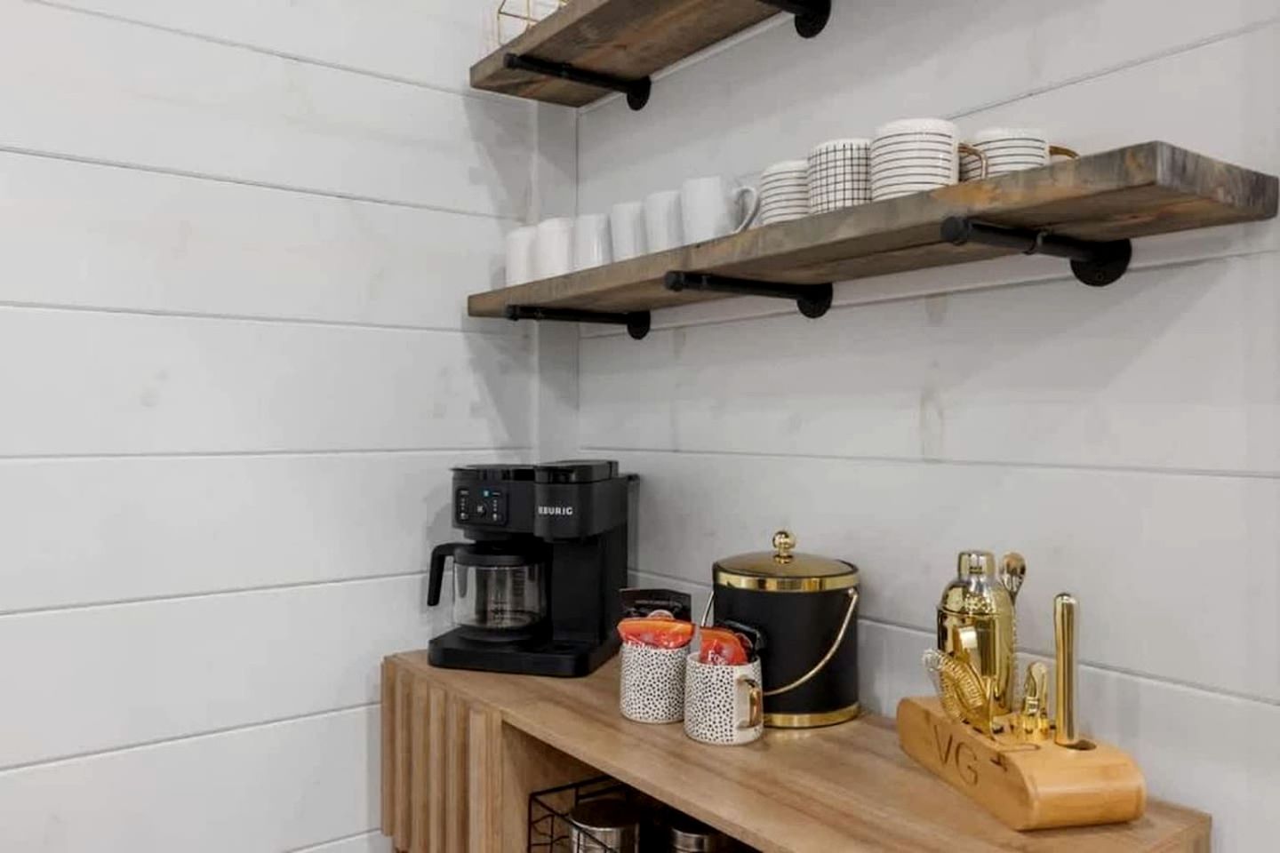 Une cuisine équipée d’une machine à café, d’une casserole et d’ustensiles de cuisine, le tout posé sur un plan de travail en bois.
